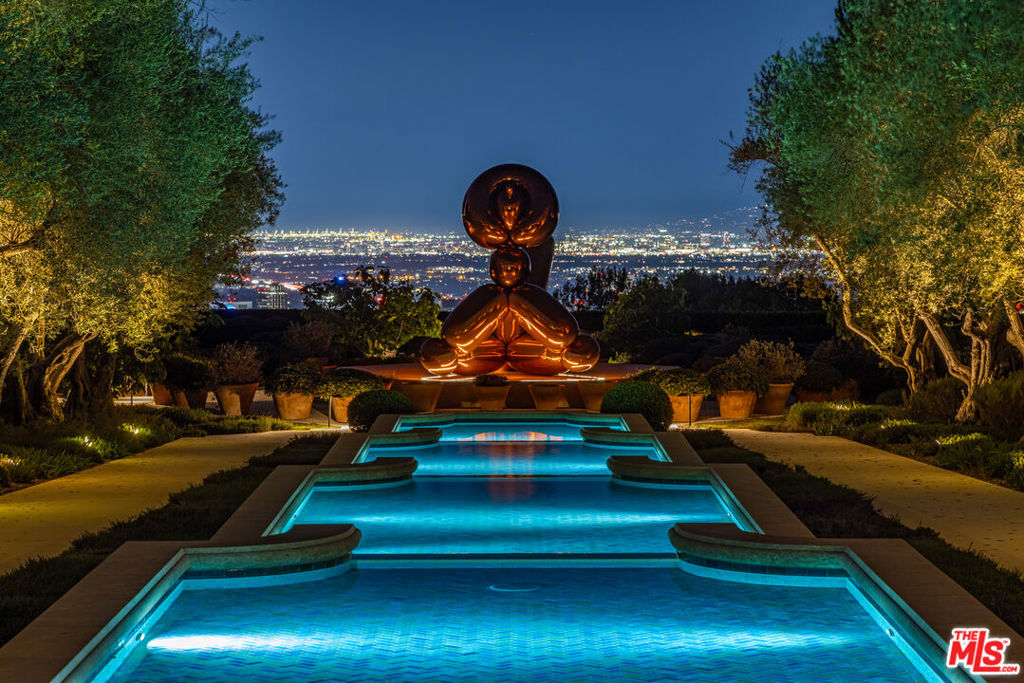 Luxury estate with illuminated pool and sculpture overlooking city lights
